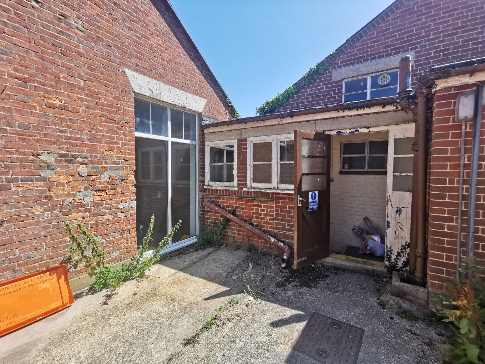 Rear courtyard between brick elevations, with an open wooden door and a large white-framed window
