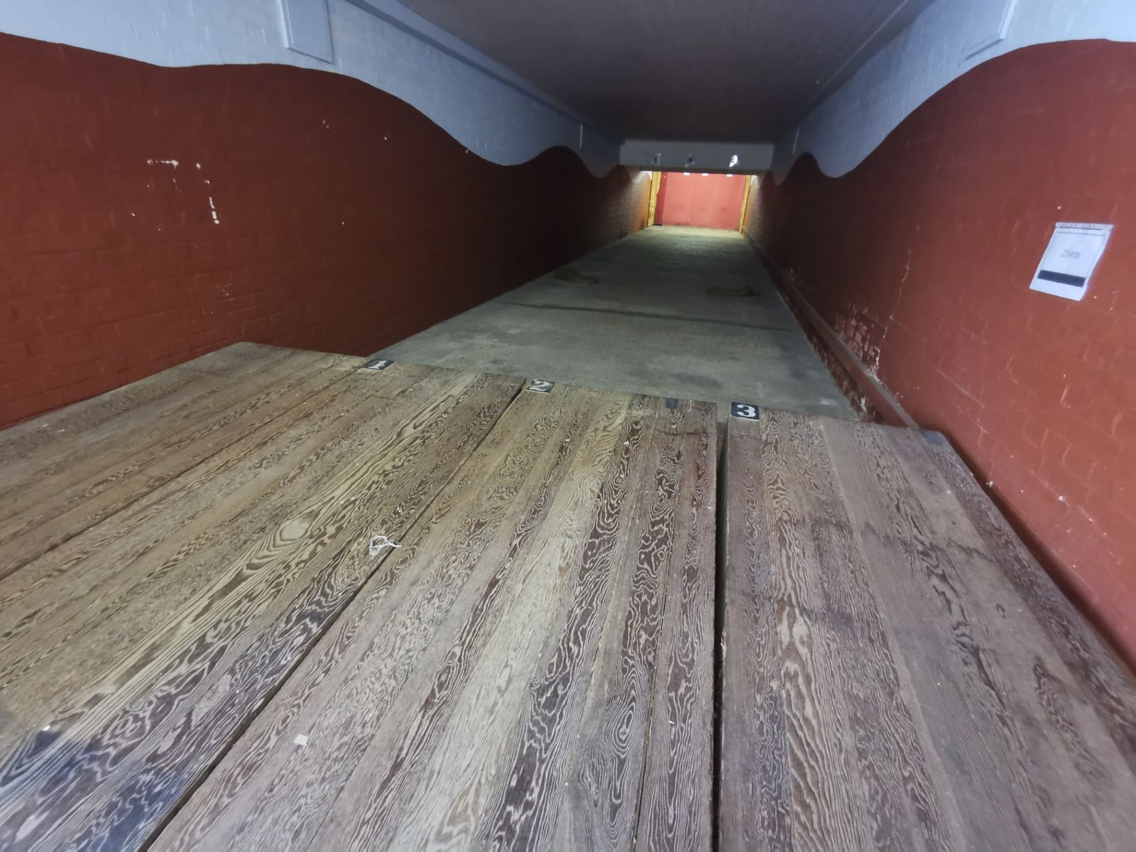 Long indoor range with red-painted walls and wooden firing-point benches numbered one to three