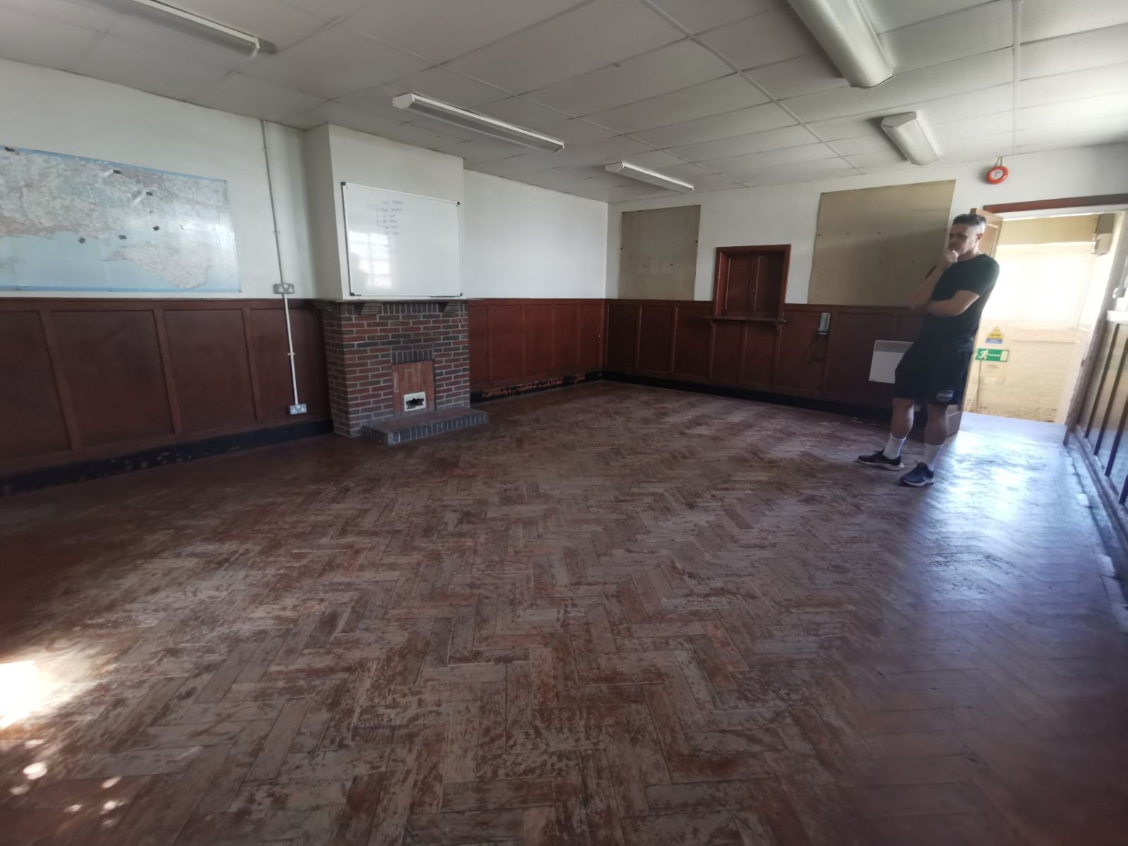 Room with a herringbone parquet floor, brick fireplace, whiteboard and a wall map of the local area